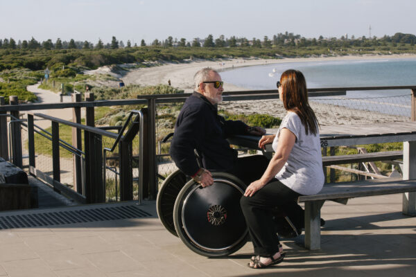 Wheelchair user and another person on accessible foreshore by beach